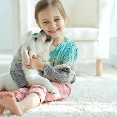 little girl with puppy on white carpet in modern living room
